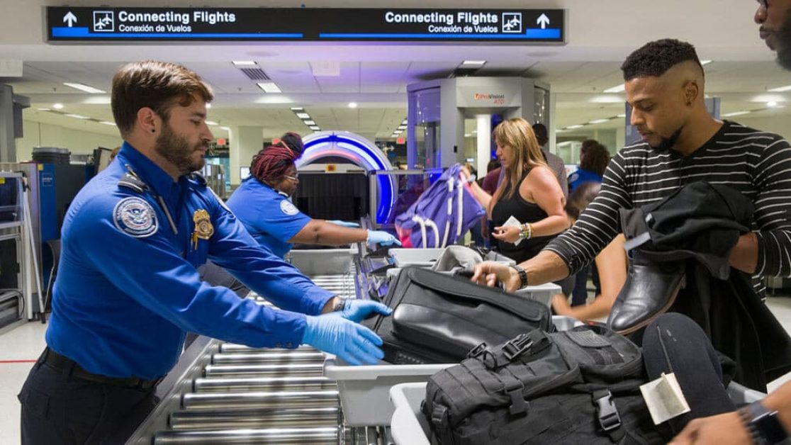 [MIAMI, FLORIDA - MAY 21: Transportation Security Administration (TSA) agents help travelers place their bags through the 3-D scanner at the Miami International Airport on May 21, 2019 in Miami, Florida. TSA has begun using the new 3-D computed tomography (CT) scanner in a checkpoint lane to detect explosives and other prohibited items that may be inside carry-on bags. (Photo by Joe Raedle/Getty Images)]